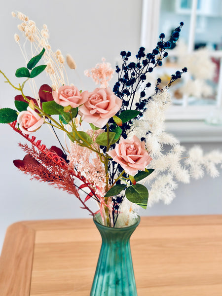 Pink roses and dry flower arrangement in translucent glass vase