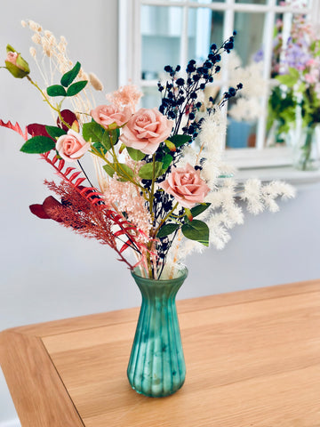 Pink roses and dry flower arrangement in translucent glass vase