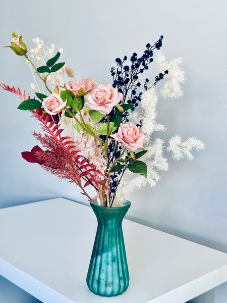 Pink roses and dry flower arrangement in translucent glass vase