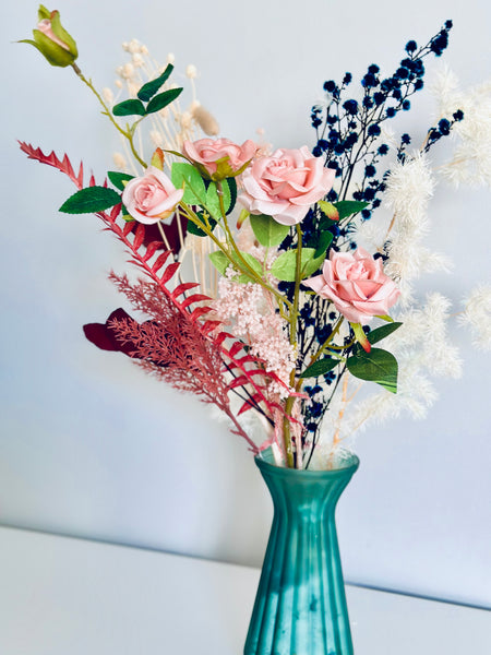 Pink roses and dry flower arrangement in translucent glass vase