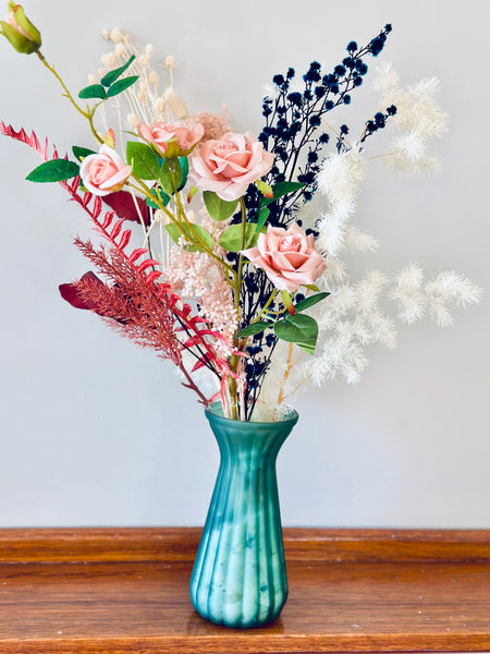 Pink roses and dry flower arrangement in translucent glass vase