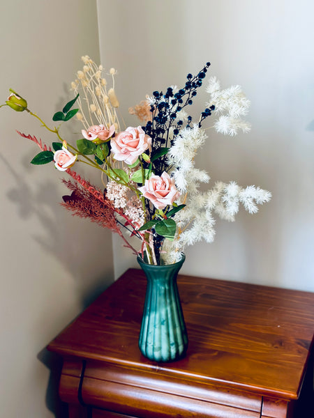 Pink roses and dry flower arrangement in translucent glass vase