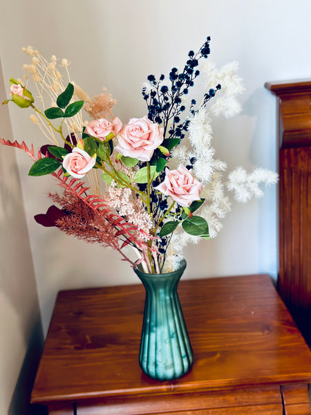 Pink roses and dry flower arrangement in translucent glass vase