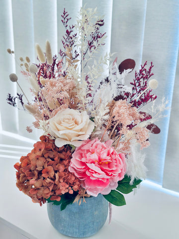 Vibrant silk and dry flower arrangement in a ceramic vase