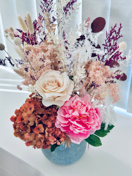 Vibrant silk and dry flower arrangement in a ceramic vase