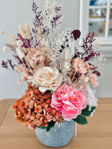 Vibrant silk and dry flower arrangement in a ceramic vase