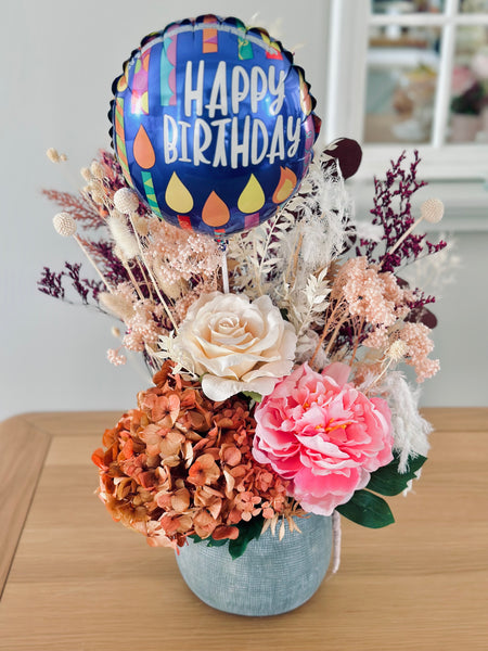 Vibrant silk and dry flower arrangement in a ceramic vase